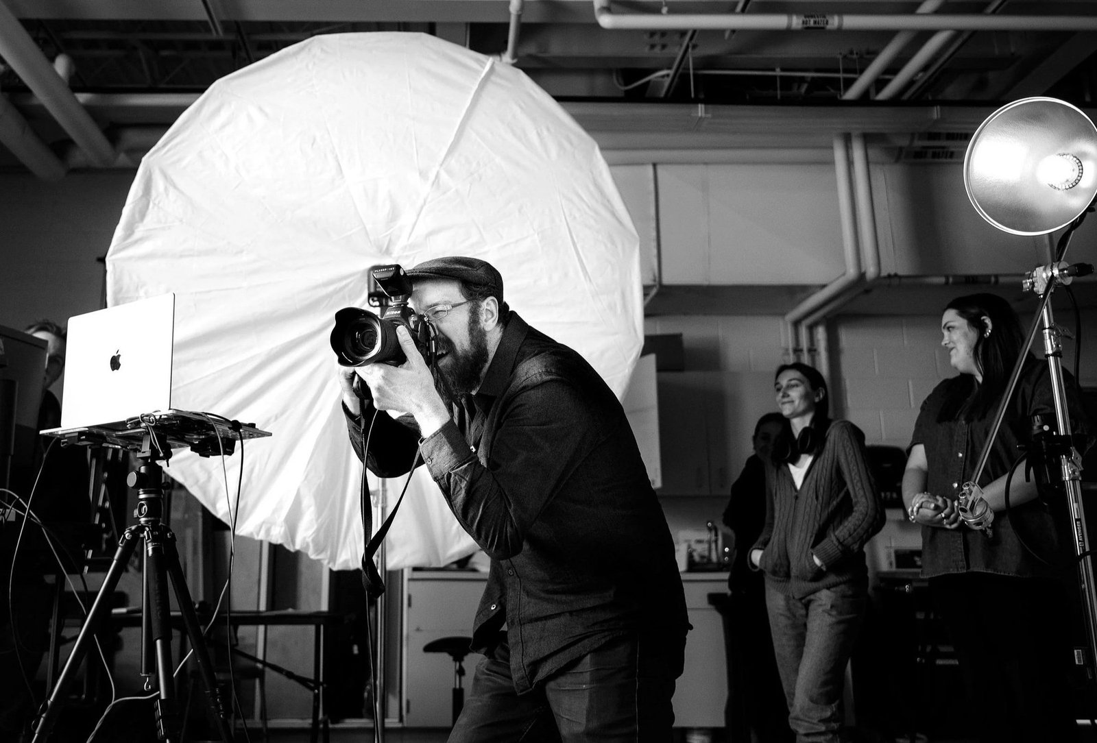 Jim Lafferty photographing on set with a large white umbrella and studio lighting